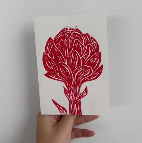 Handgemachte Linoldruckkarte mit roter Artischocke auf naturweissem Hintergrund. Minimalistisches, botanisches Motiv mit klaren Linien und organischer Struktur. Jede Karte ist handgedruckt und ein Unikat – ideal als stilvolle Grusskarte oder Dekoration.