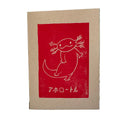 Handgemachte Linoldruckkarte mit rotem Axolotl-Motiv und japanischer Schrift („アホロートル“) auf naturfarbenem Papier. Verspieltes, minimalistisches Design, handgedruckt im Linolschnittverfahren. Ideal als humorvolle Grusskarte oder Geschenkidee für Tierliebhaber.