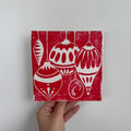 Handgemachte Linoldruckkarte mit roten und weissen Weihnachtskugeln. Grafisches, festliches Motiv mit fünf unterschiedlich geformten Ornamenten, inspiriert von klassischen Christbaumdekorationen. Minimalistisches Design mit handwerklichem Charakter, ideal als stilvolle Weihnachtskarte oder Dekoration.